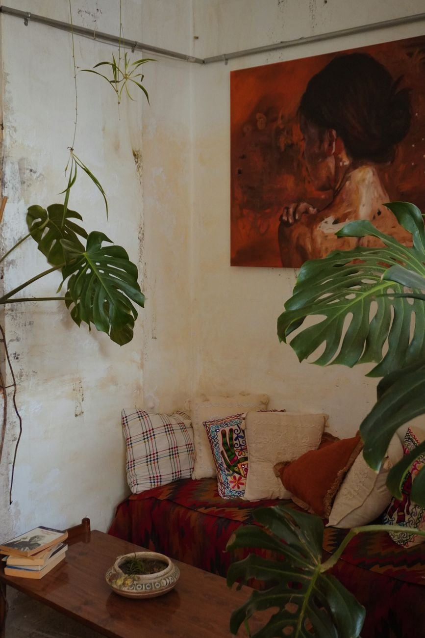 a living room with a couch plants and a painting